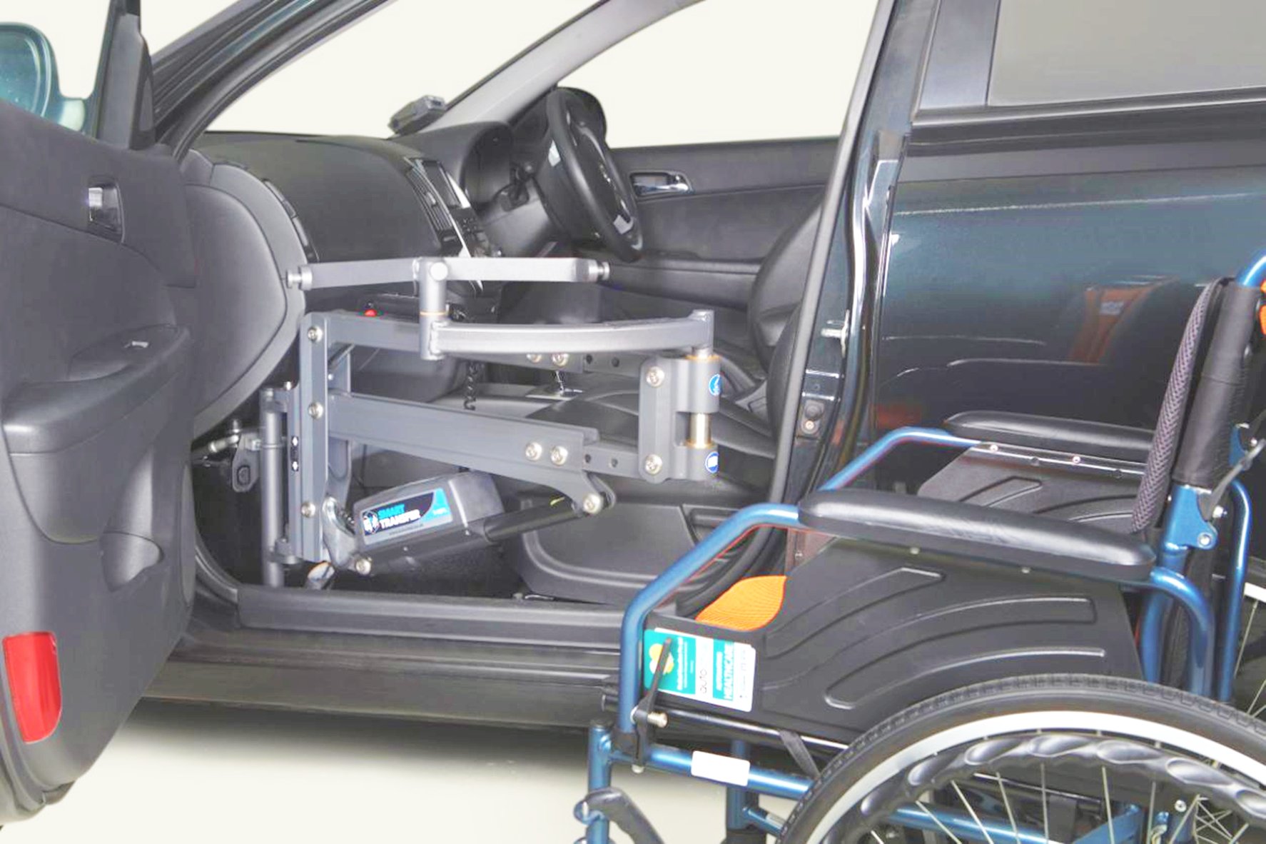 Autochair Smart Transfer device placed at the lower side of the front passenger seat of a car, showing a wheelchair next to the car.