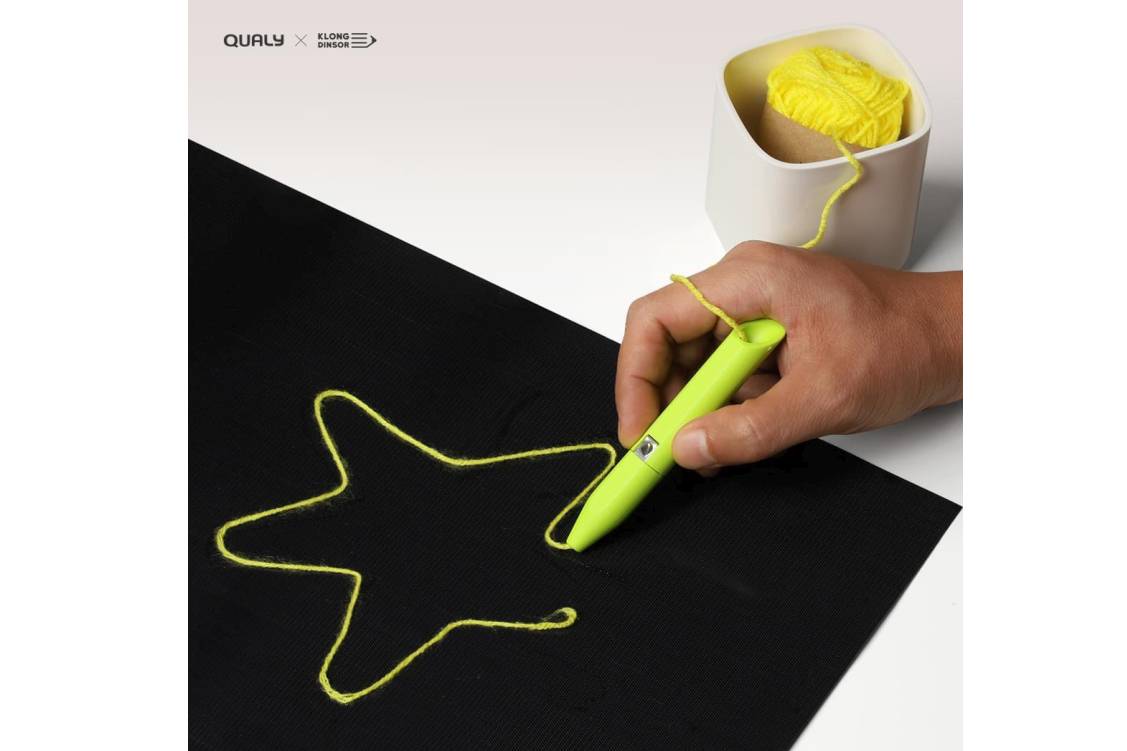 Lensen Drawing Kit with Velcro sheet in black, threading pen in green and yarn in yellow. Photo shows a man's hand holding the threading pen with the yarn shown through it and the outline of a star that he has drawn with the yarn sticking on the Velcro sheet.