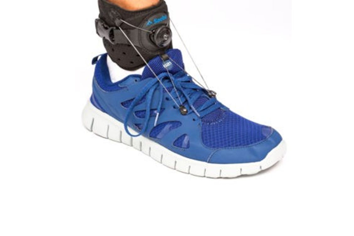 Saebo Step Foot Drop Brace as worn on a person's right ankle with shoes in blue.